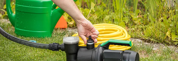 Person montiert Gartenpumpe auf Rasen.